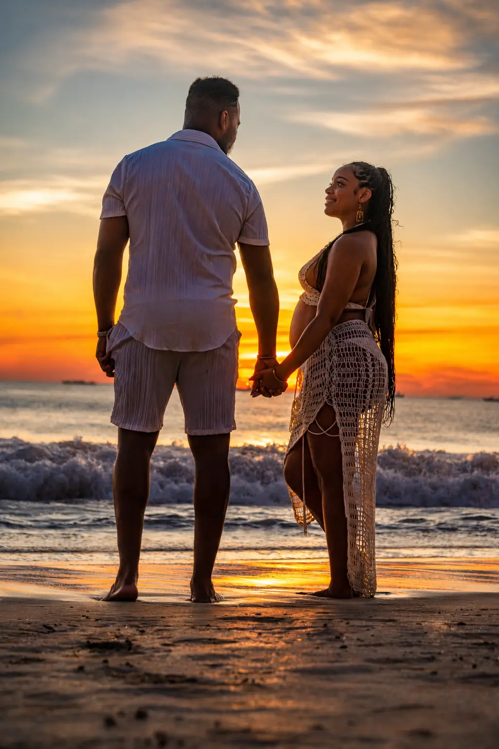 Couple holding hands on the shoreline at sunset, expecting mother looking up at her partner