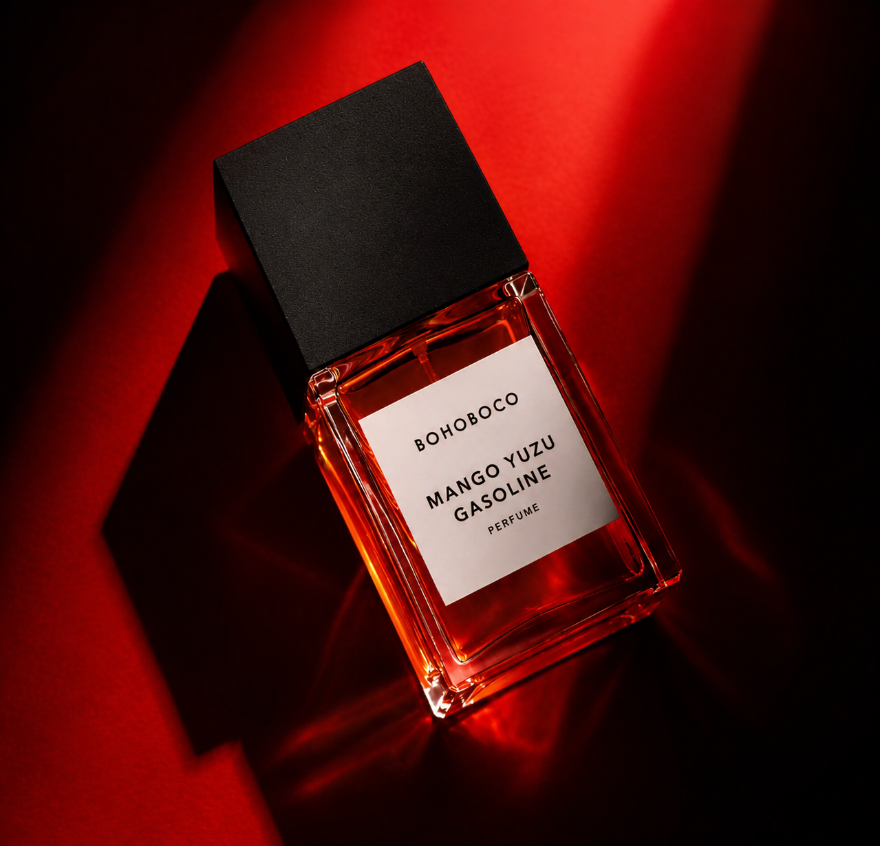 Bohoboco Mango Yuzu Gasoline perfume bottle lit with hard red light and graphic shadows