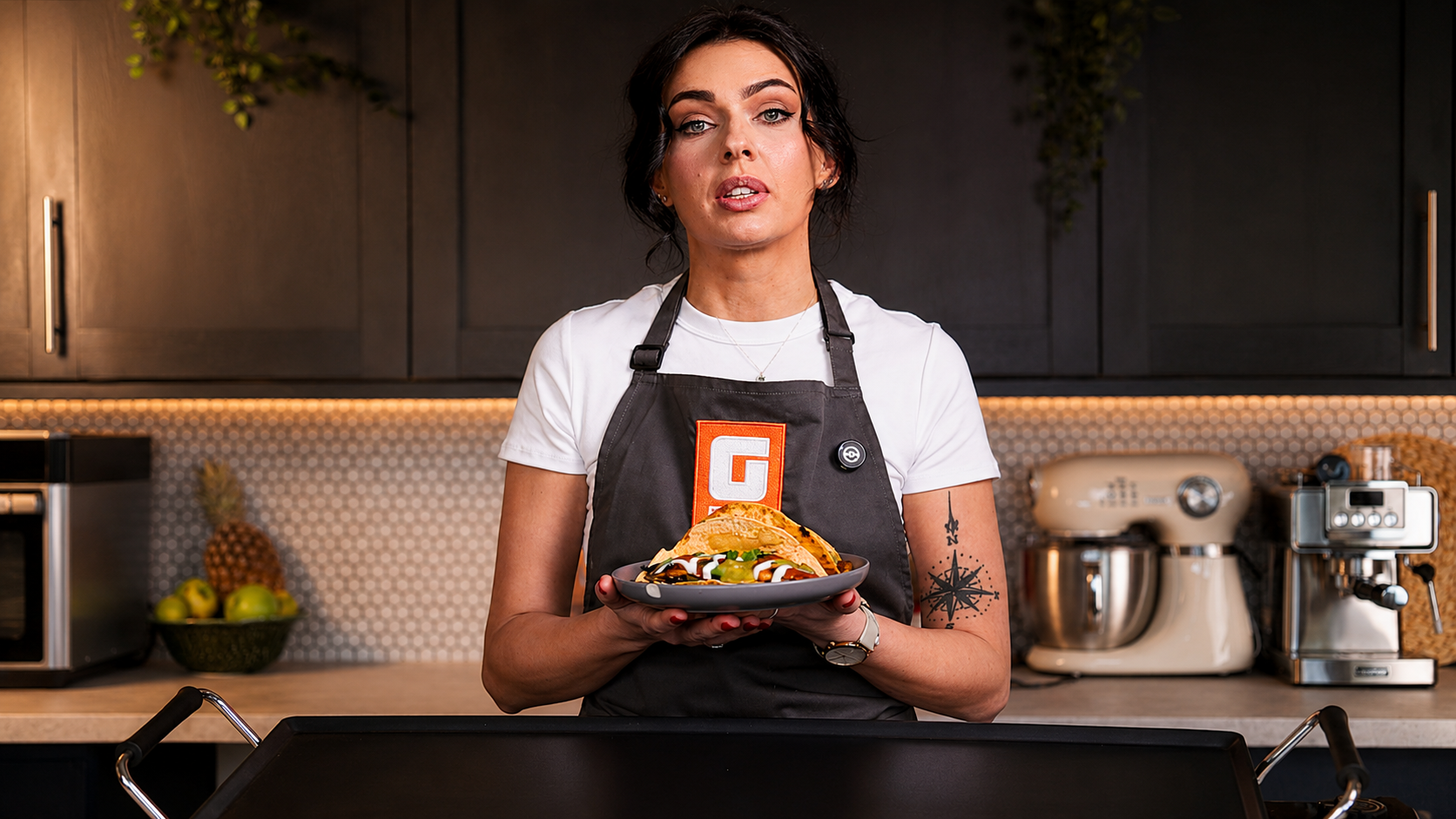 Presenter holding a finished plate to camera on the Geepas cooking series set