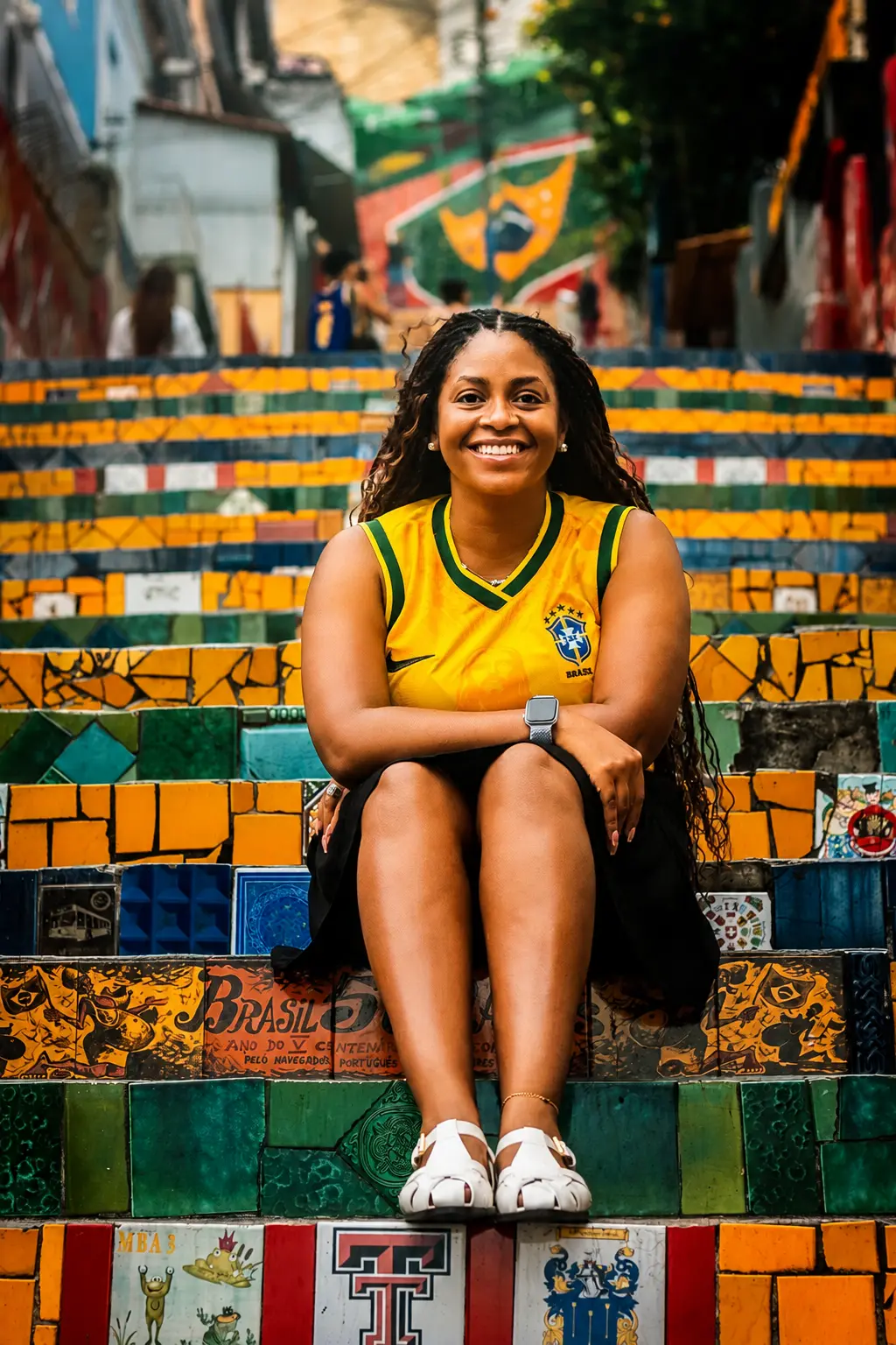 Woman in a yellow Brazil jersey sitting and smiling on the mosaic Selarón Steps