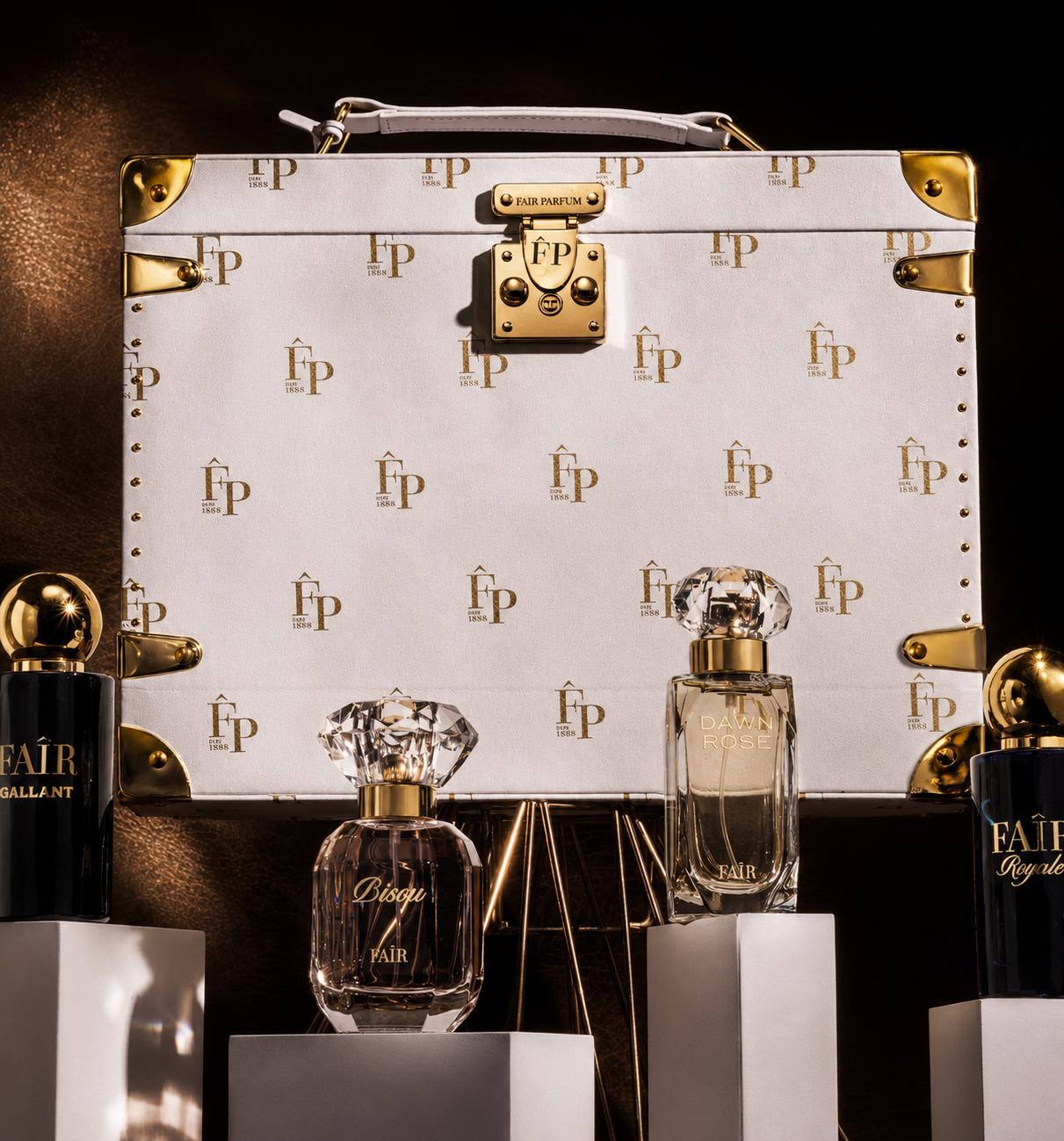 Fair Parfum monogrammed white trunk behind a row of glass fragrance bottles on white plinths