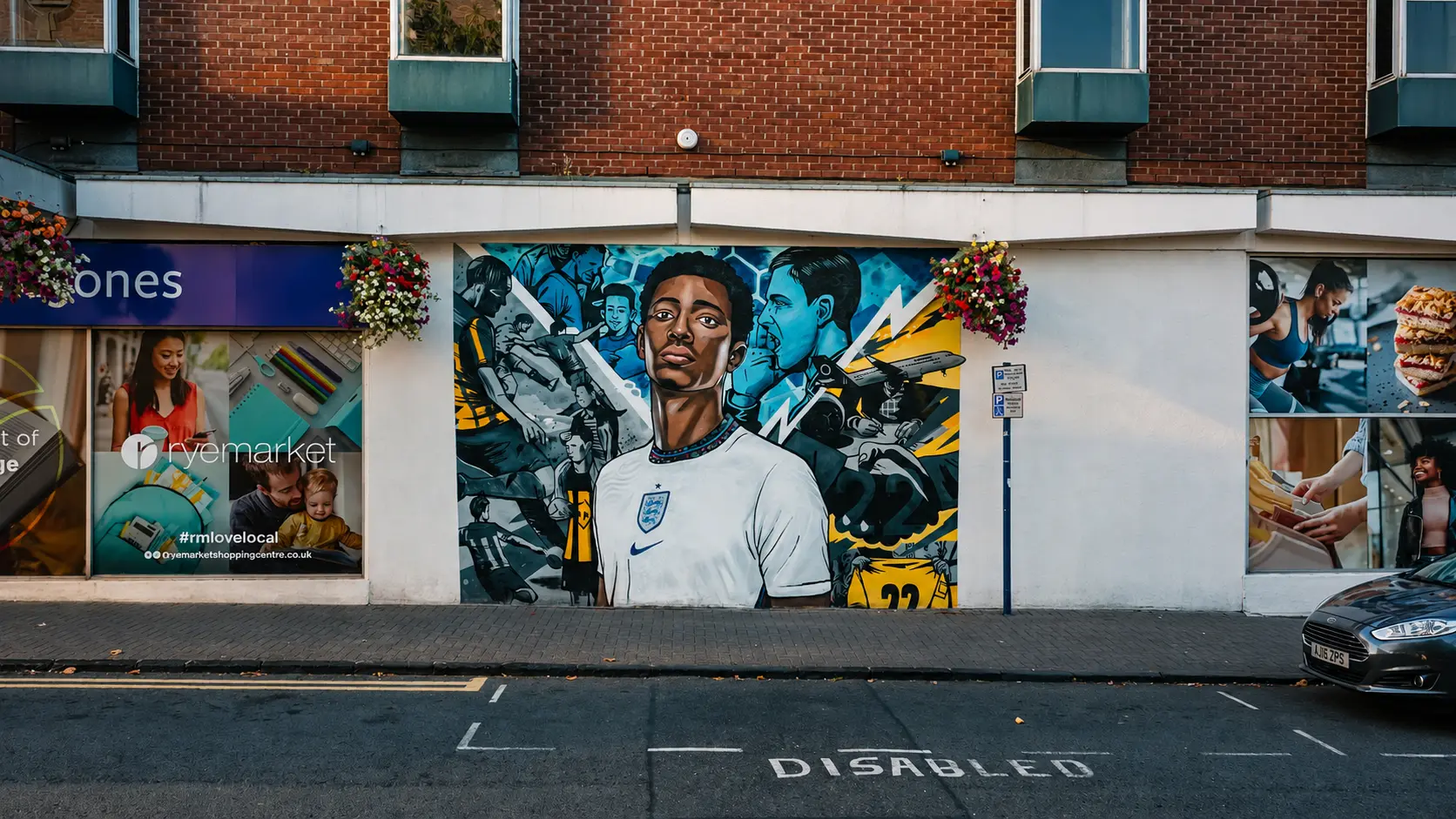 Street mural of a footballer painted on a wall beside Ryemarket shopping centre