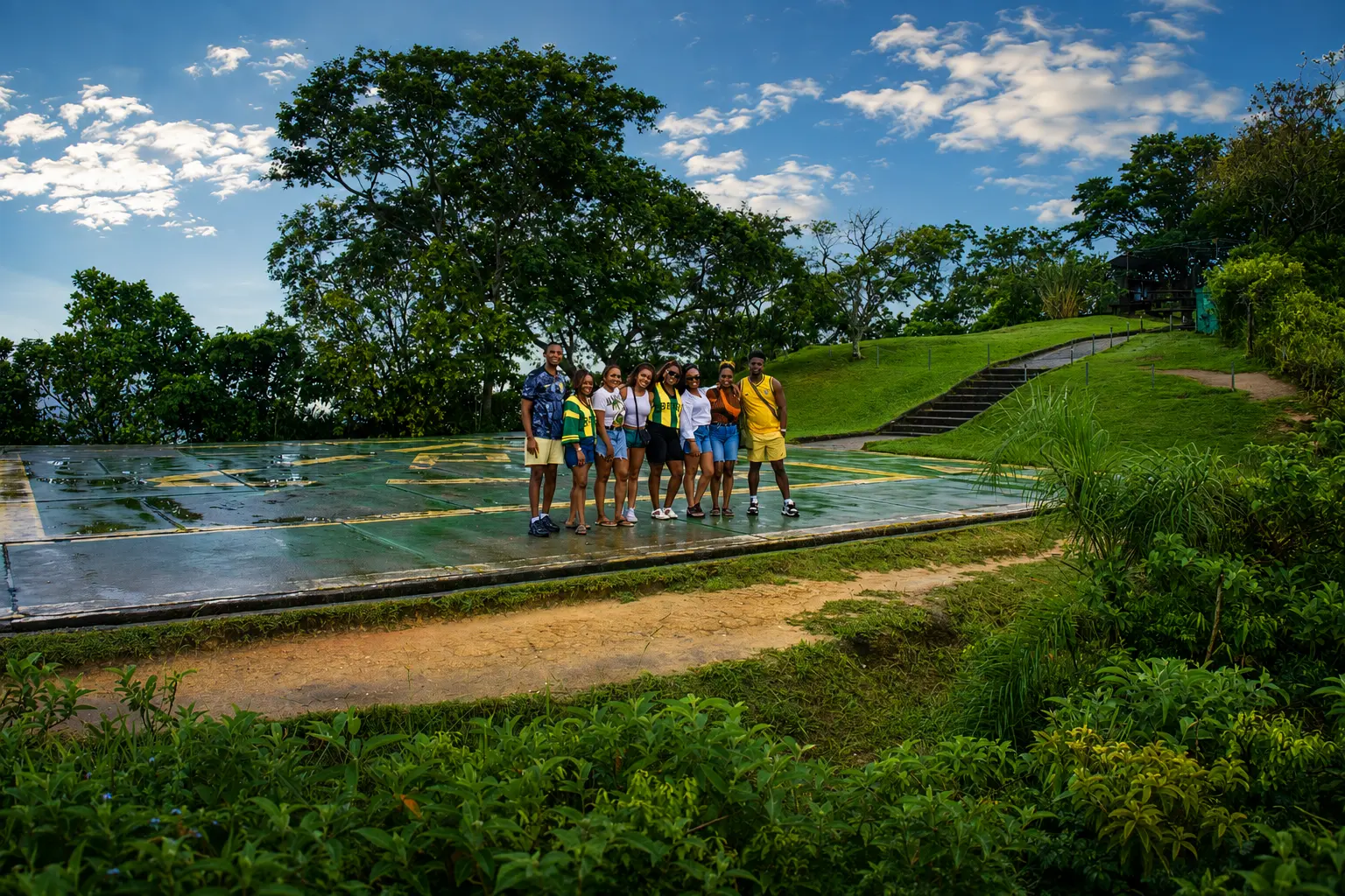 Group of friends posing on a wet helipad on a green hilltop after rain